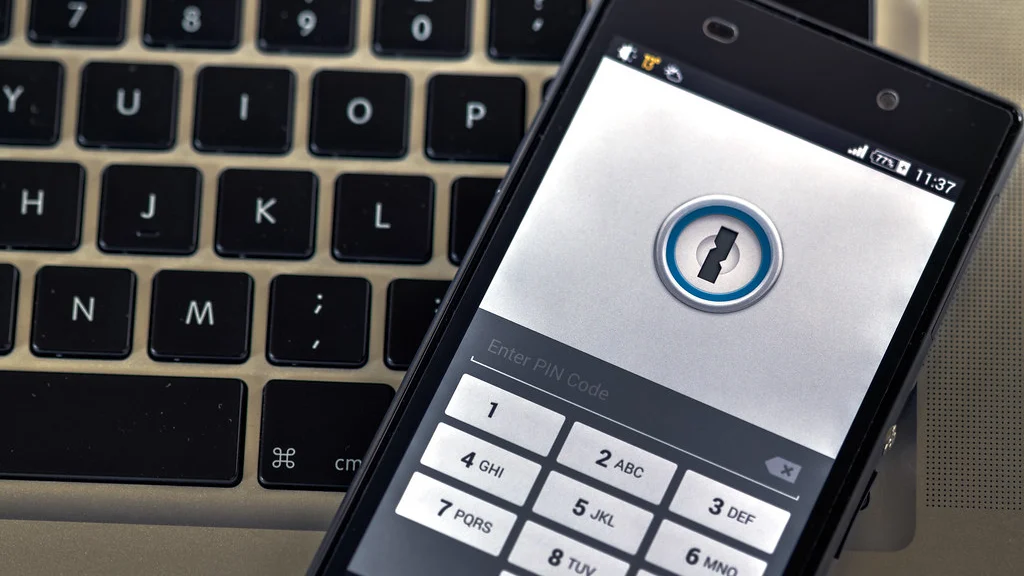 Password manager application open on a phone resting on a laptop keyboard