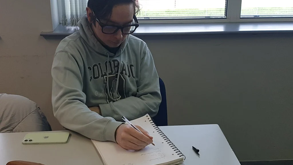 Person wearing smart glasses while writing notes at a desk