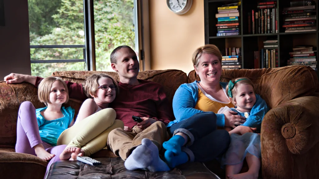 Family sitting on a couch and watching a movie together at home