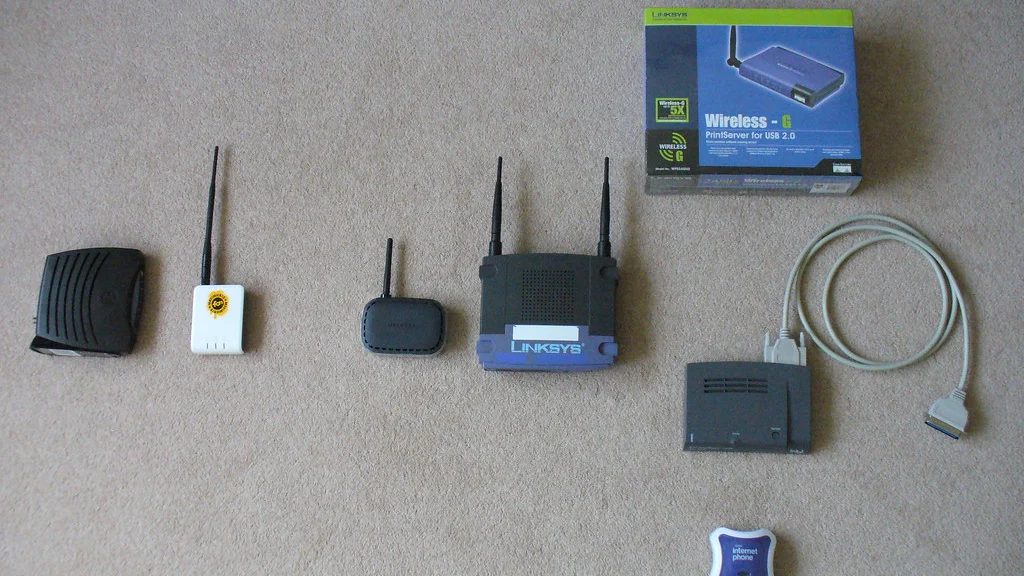 Several home Wi-Fi routers and network adapters arranged with an Ethernet cable