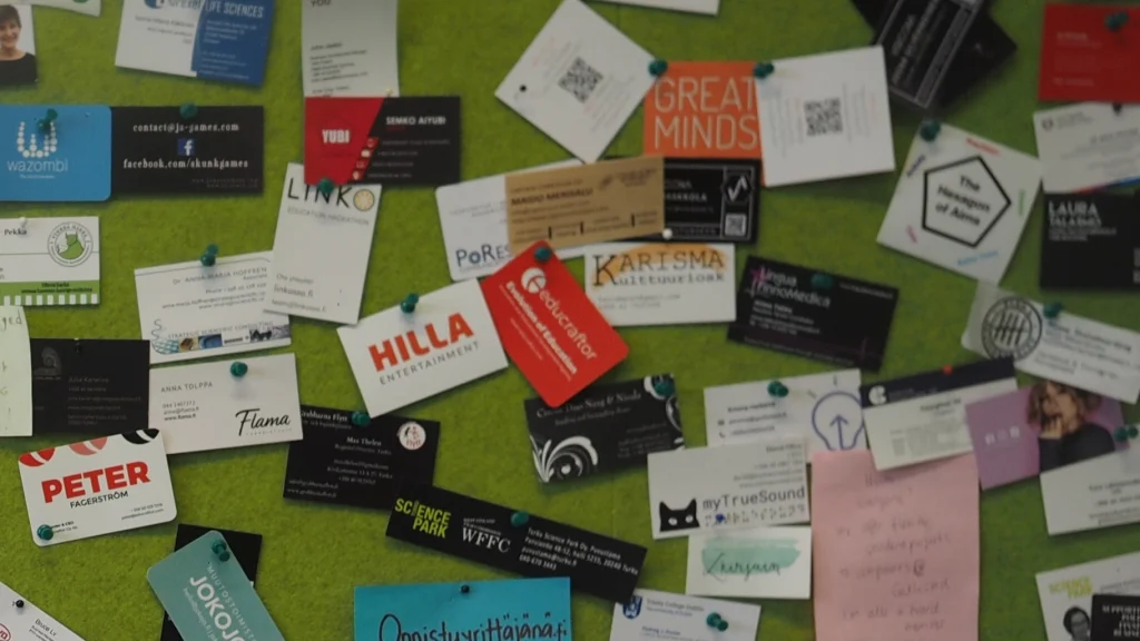 Real printed business cards in varied shapes and colors displayed on a wall