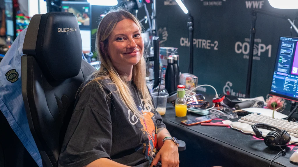 Real streamer seated at a broadcast desk with monitor, keyboard, lights, and headphones